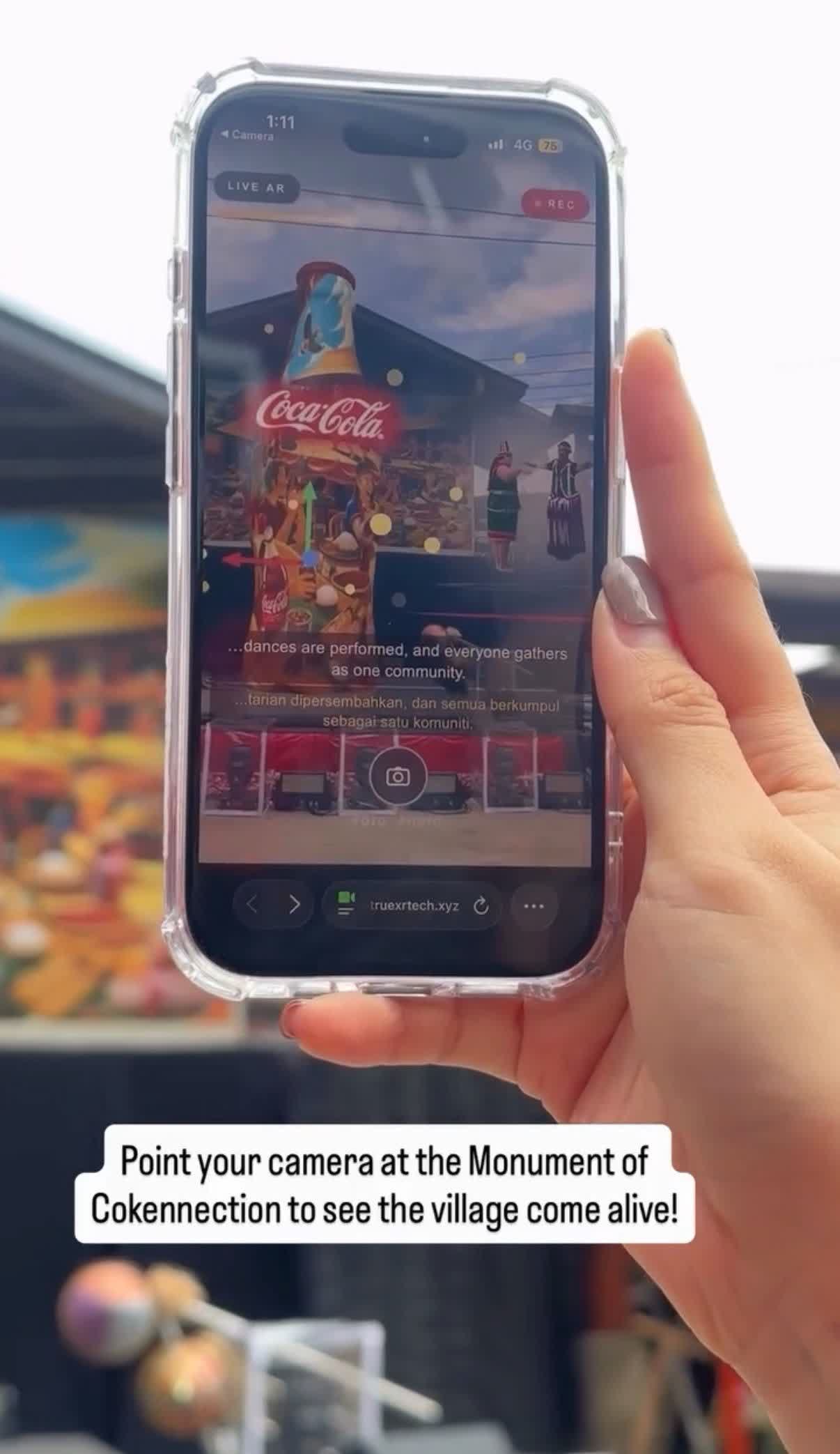 Visitor viewing the AR experience on a phone at Kampung Annah Rais, with the caption 'dances are performed, and everyone gathers as one community'